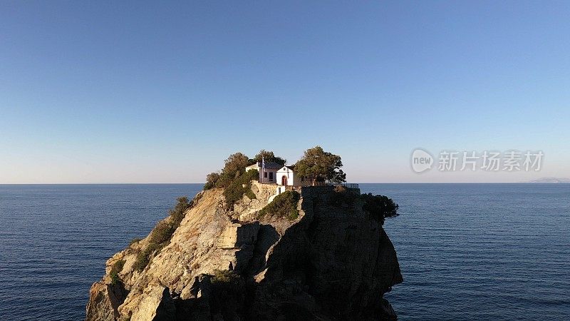 无人机拍摄的风景如画的圣约翰教堂建在著名的Mama Mia电影悬崖上，Skopelos岛，斯波拉迪斯，希腊。日落。